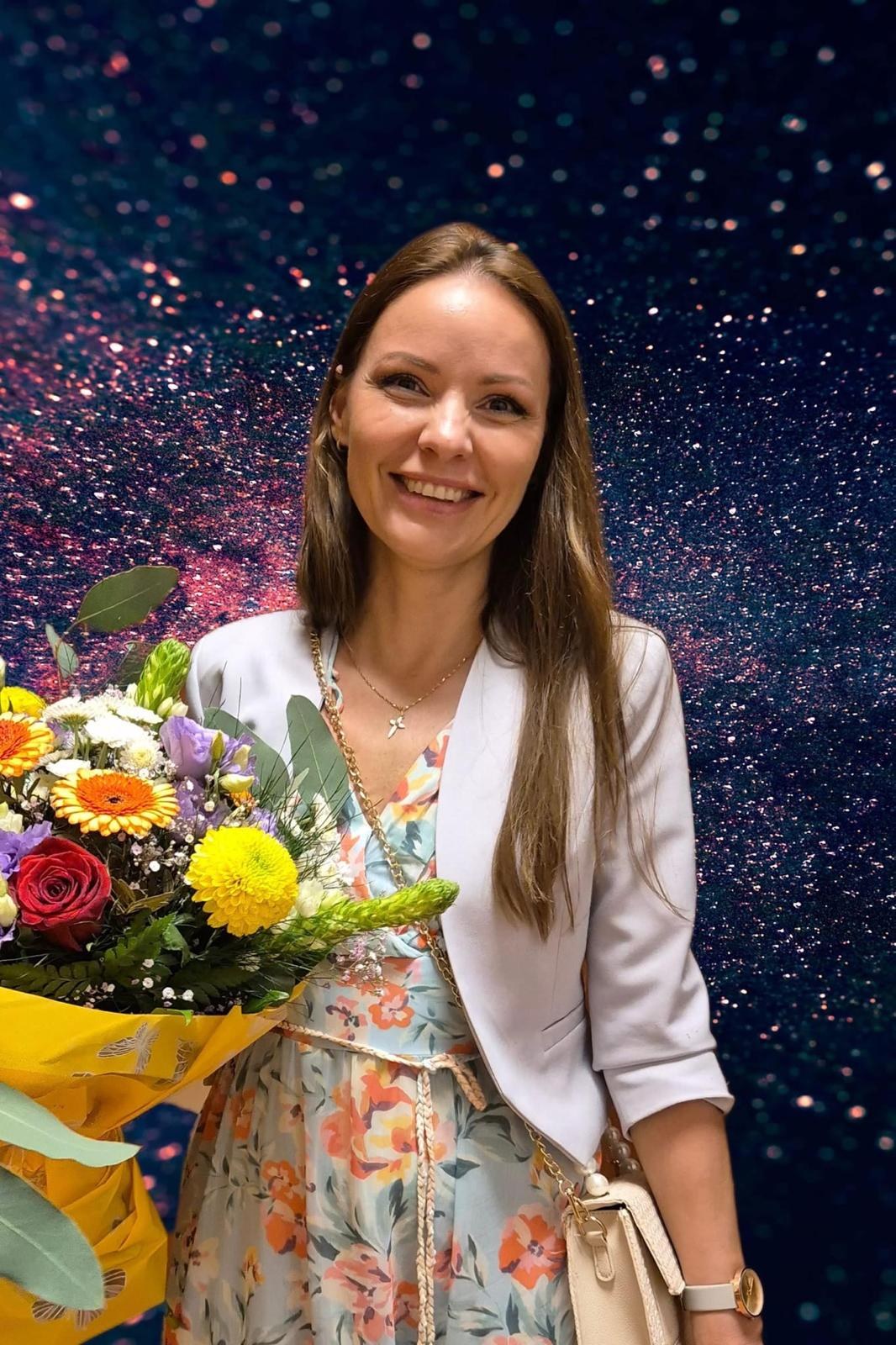 Olga Yurieva, certified nutritionist, smiling with flowers
